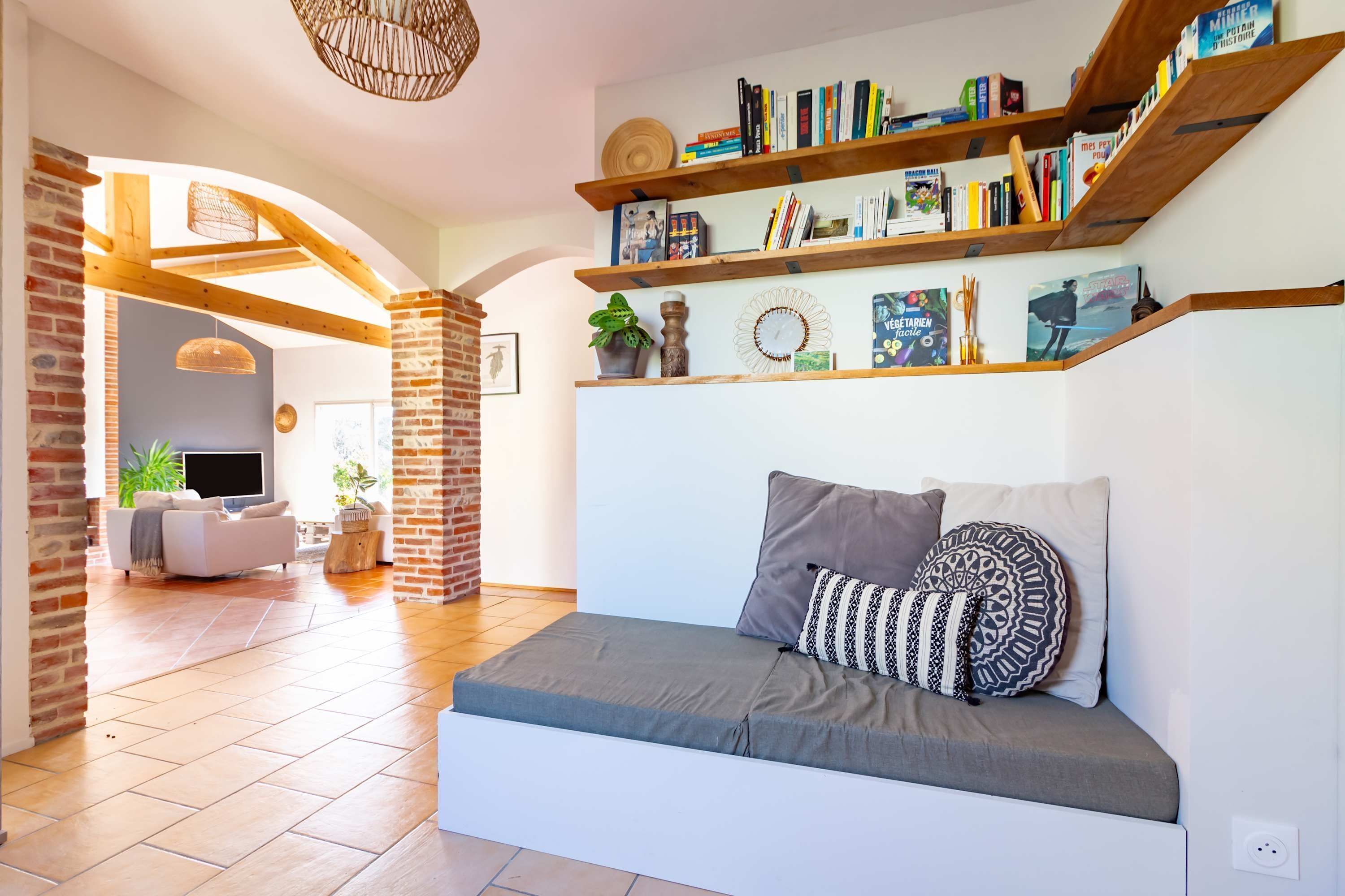 A cozy living area with a sofa, bookshelves, and a TV in the background.