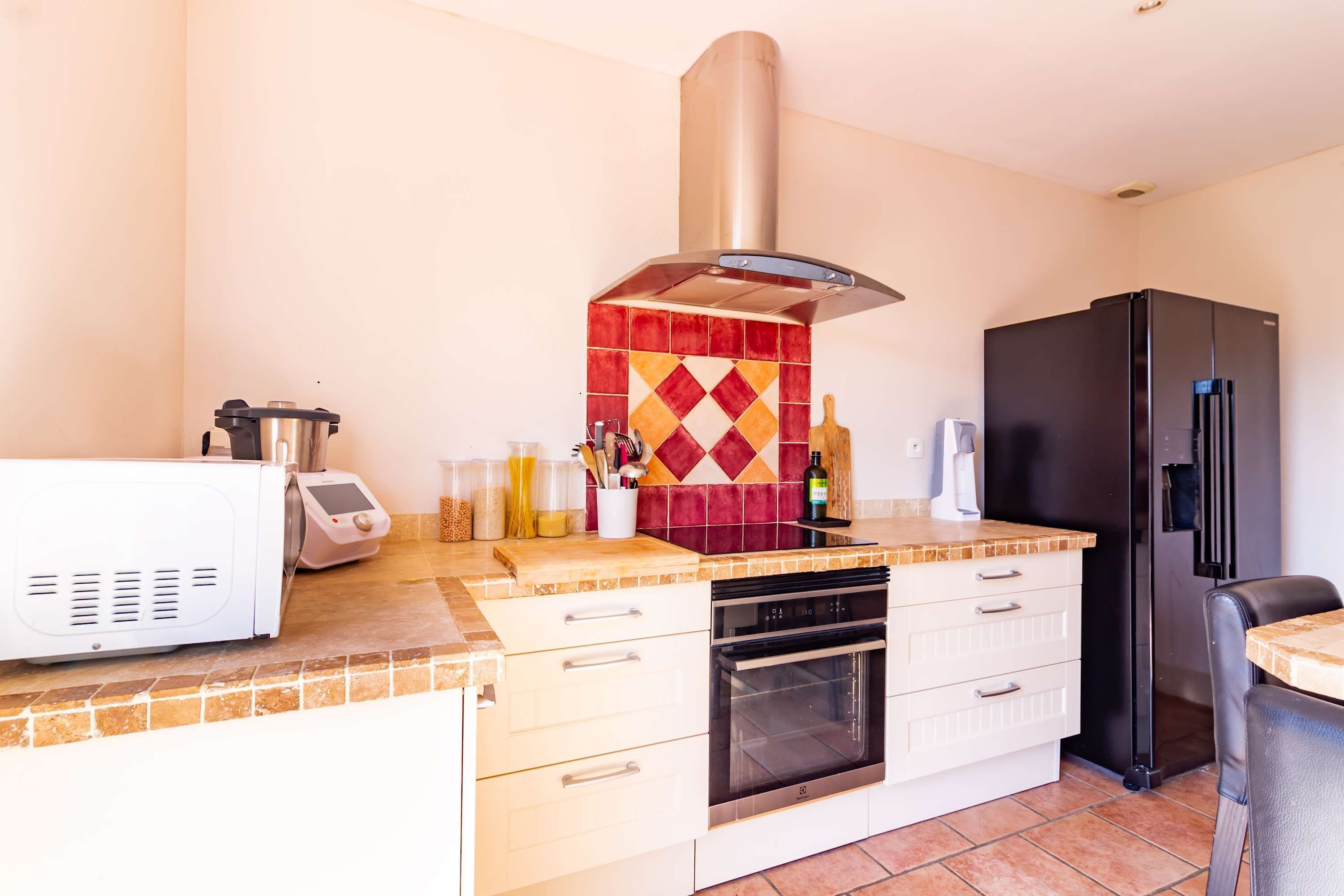 A compact kitchen with a microwave, oven, and a black refrigerator.