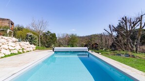 A rectangular swimming pool with a clear blue water surface, surrounded by a stone wall and greenery. - La Tendresse - 10p - Piscine - Jardin (Mondonville)