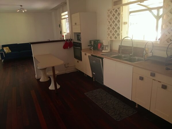 Cocina compacta con mesa de comedor, horno integrado, fregadero y lavavajillas.