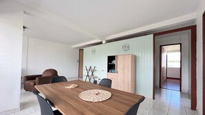 A dining area with a wooden table, black chairs, and a light blue wall with a wooden cabinet.