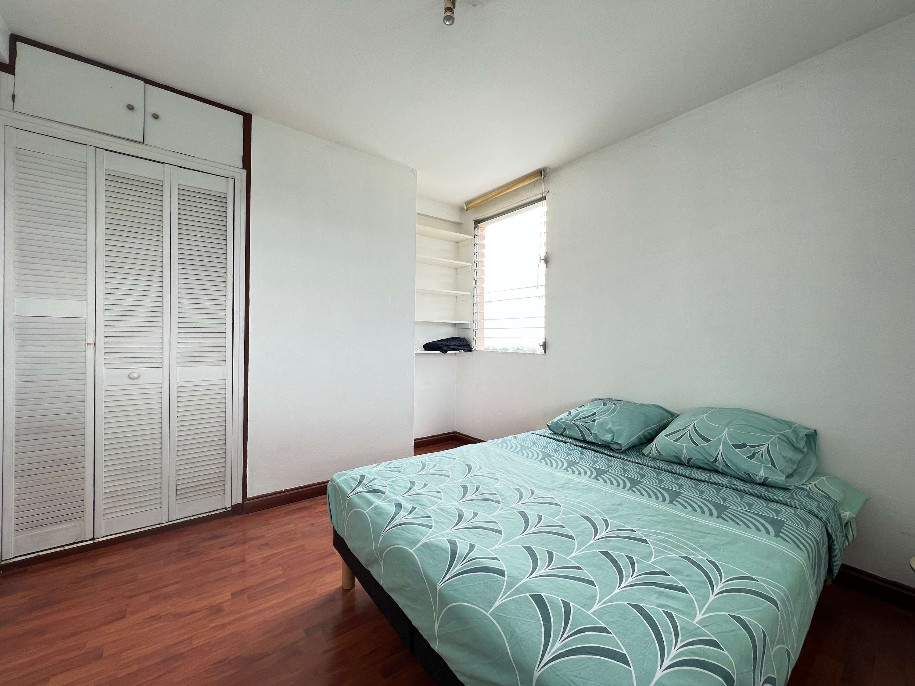 Ein Schlafzimmer mit einem Bett, einem Kleiderschrank und einem Fenster.
