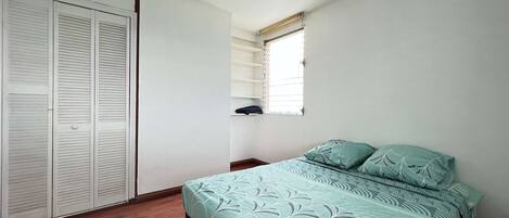 Ein Schlafzimmer mit einem Bett, einem Kleiderschrank und einem Fenster.