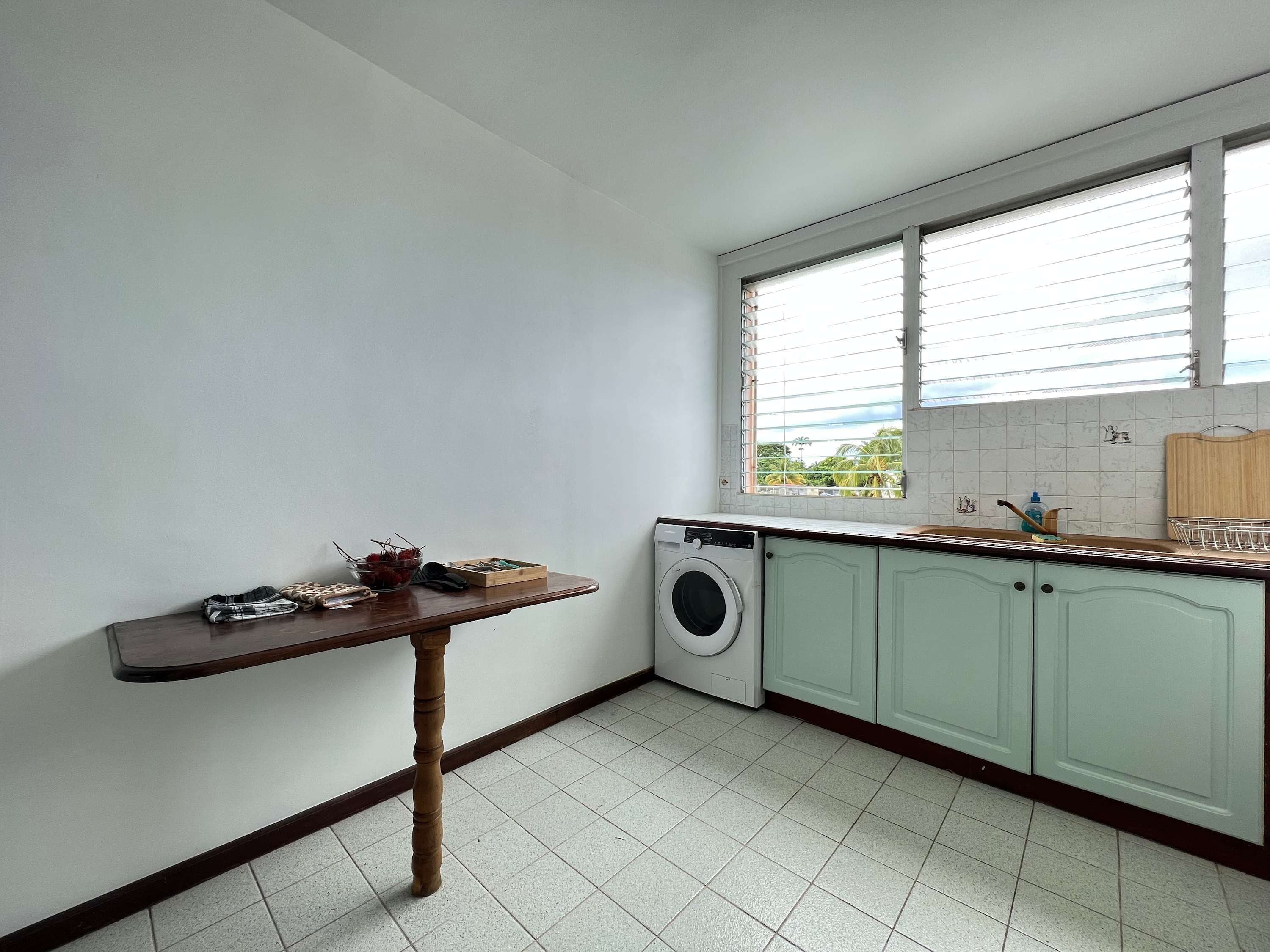 Une buanderie équipée d’un lave-linge, d’un étendoir et d’une fenêtre avec des stores.