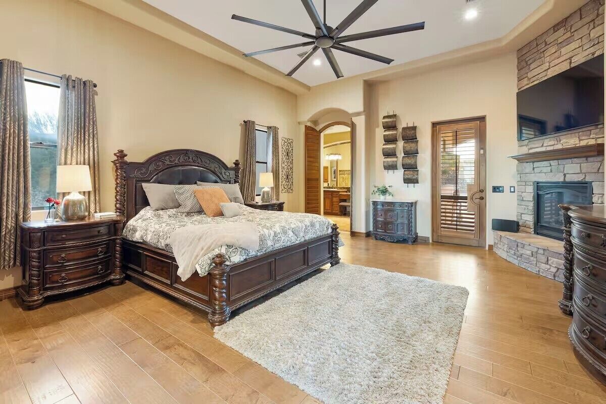 A spacious bedroom with a large bed, wooden headboard, and a fireplace.