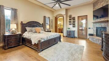 A spacious bedroom with a large bed, wooden headboard, and a fireplace.