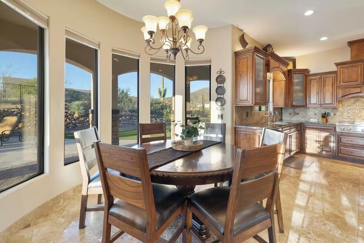 A spacious kitchen with wooden cabinets, a large dining table, and a chandelier.