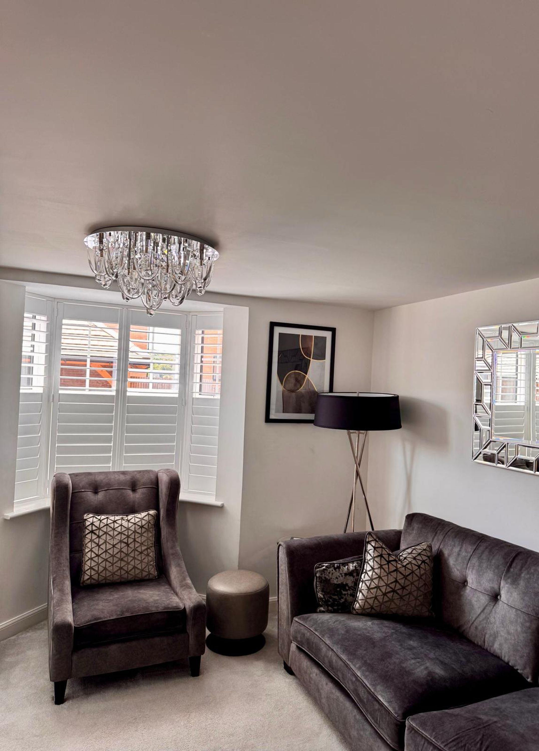 A living room with a chandelier, a sofa, a chair, and a floor lamp.