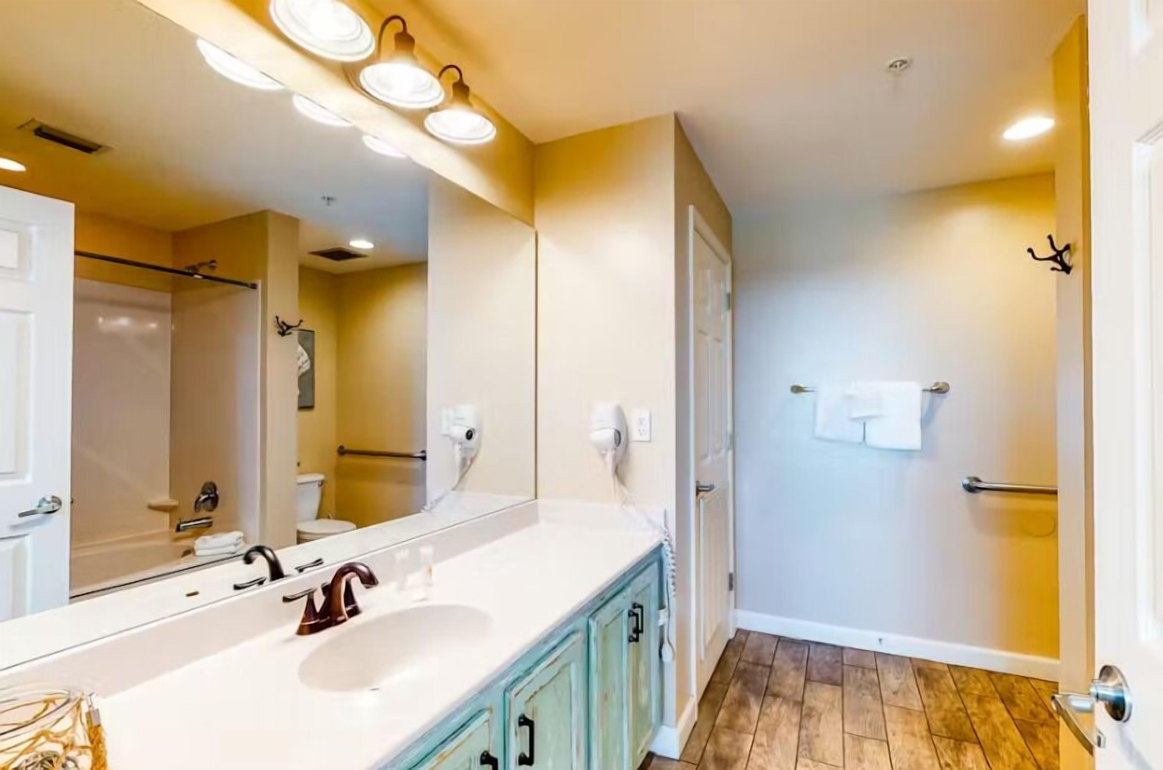 A bathroom with a white sink, a mirror, and a shower.