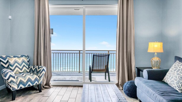 Ett rum med utsikt över havet, en soffa, en fåtölj och en lampa.