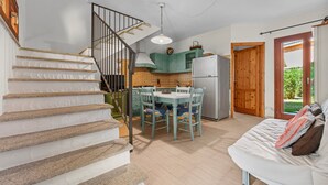 A staircase leading to a kitchen with a dining table and chairs, a refrigerator, and a wooden door. - Villa 'Livia' with Shared Pool, Private Terrace and Garden (Sant'Anna Arresi)
