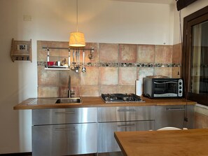 A modern kitchen with stainless steel appliances, a gas stove, a built-in oven, and a hanging light fixture.