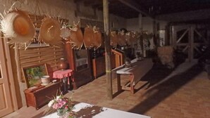 An outdoor dining area with a long table, several chairs, and a decorative arrangement of hats on the wall. - Bed and breakfast (Glatigny)