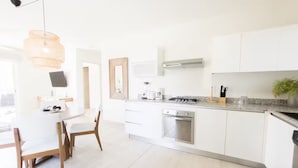Une cuisine moderne avec des meubles blancs, une cuisinière à gaz, un four à micro-ondes et un évier.