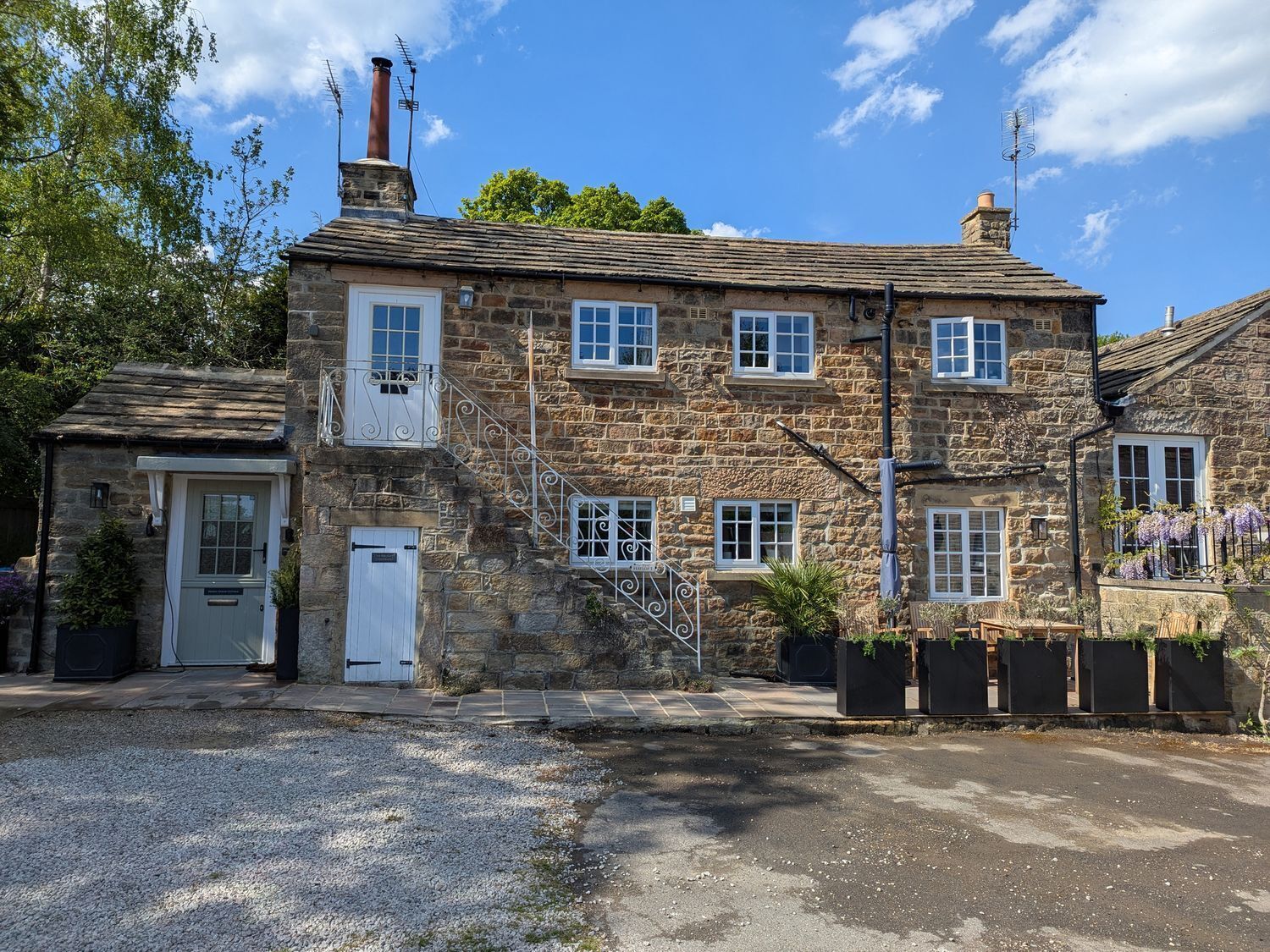 A stone house with a white door, multiple windows, and a chimney.