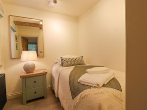 Une chambre à coucher avec un lit, une table de chevet avec une lampe, un miroir et un radiateur.