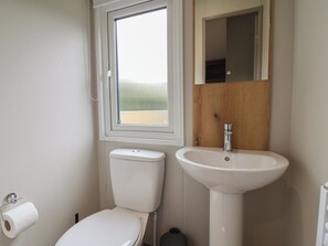 A bathroom with a toilet, sink, and window. - The Oaks 2 Bedrooms (Northwich)