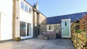 A courtyard with a stone wall, a green door, and a wicker sofa. - Yr Hen Felin (Dyffryn Ardudwy)