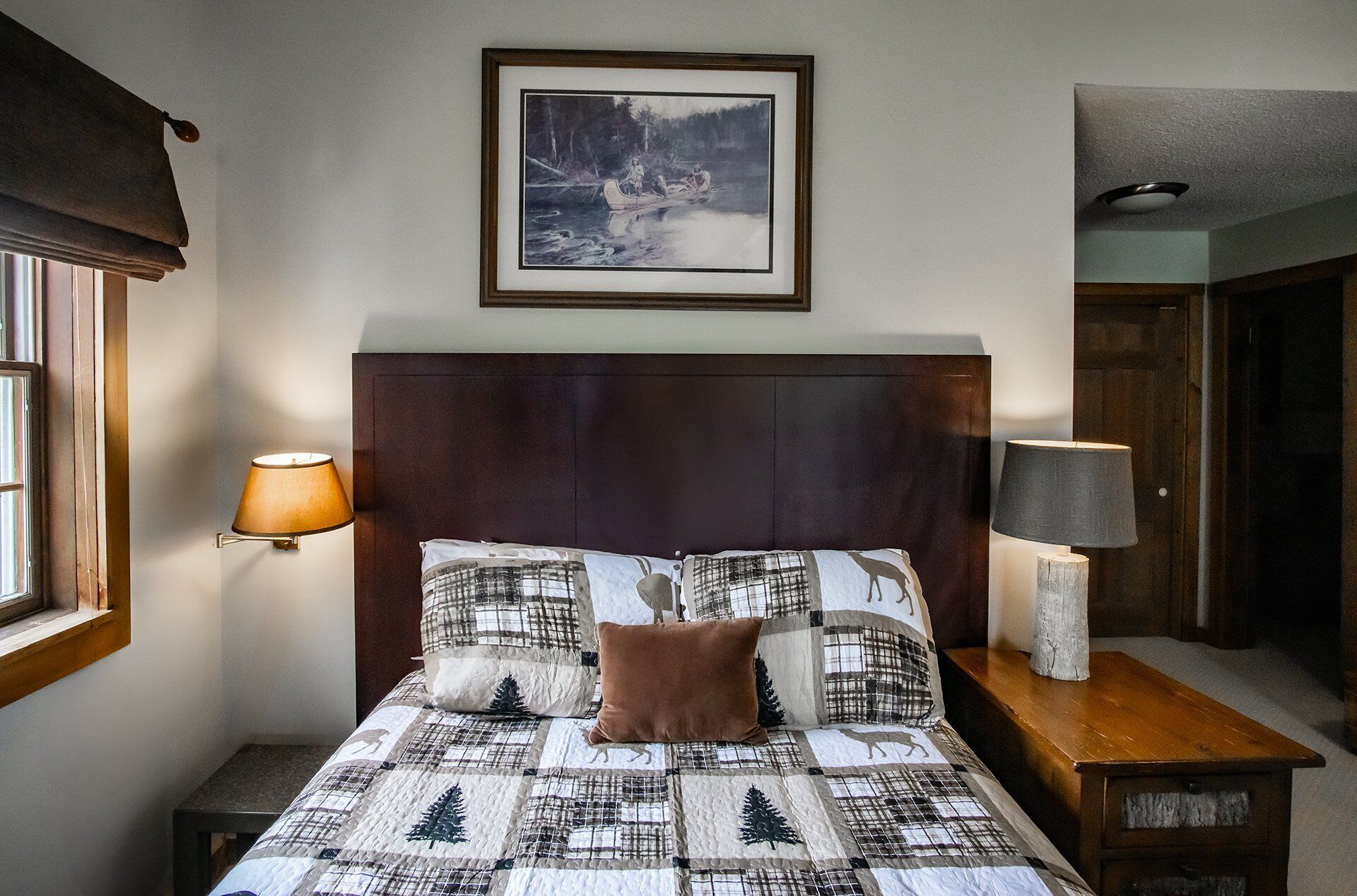A neatly made bed with a quilted pattern, two bedside lamps, and a framed picture above the bed.