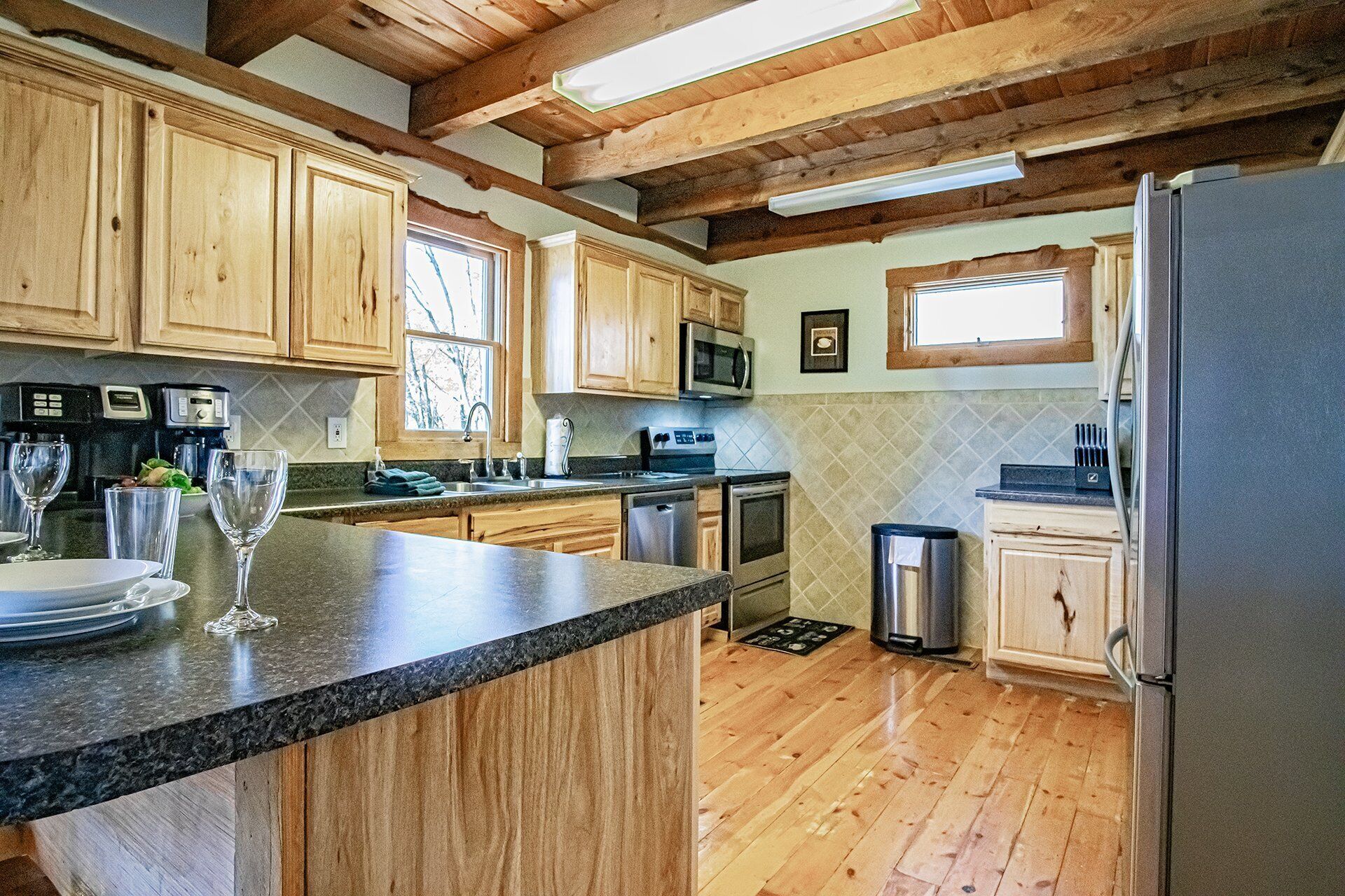 A kitchen with wooden cabinets, a granite countertop, stainless steel appliances, and a wooden floor.