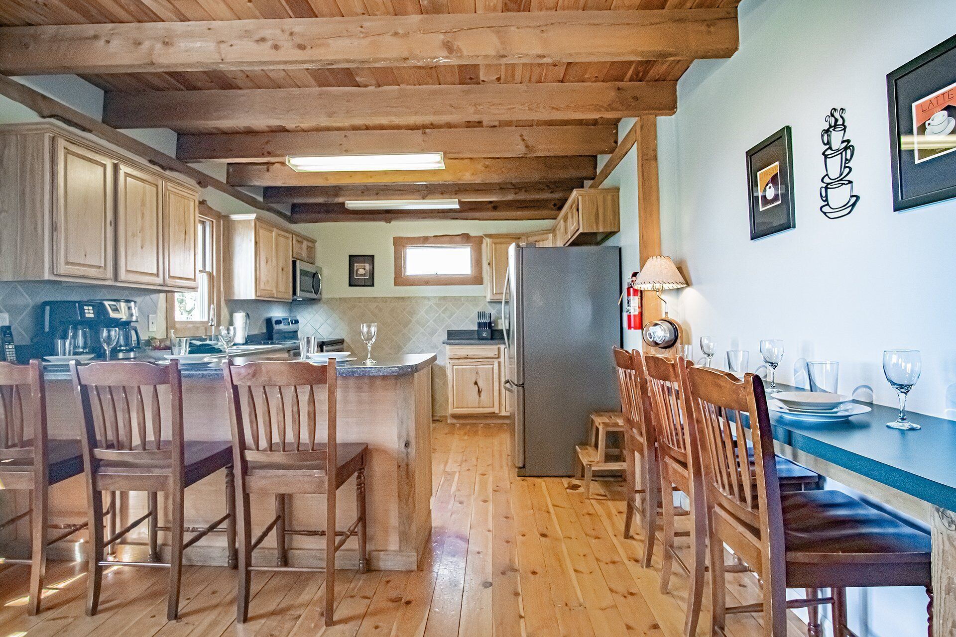 A kitchen with wooden cabinets, a central island, and a dining area with chairs and a table.