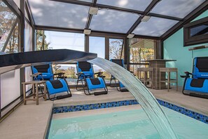 A pool area with a glass-enclosed roof, blue lounge chairs, and a tiled pool edge. - Autumn Escape Indoor Plunge Pool + 22 Guests (Snowshoe)