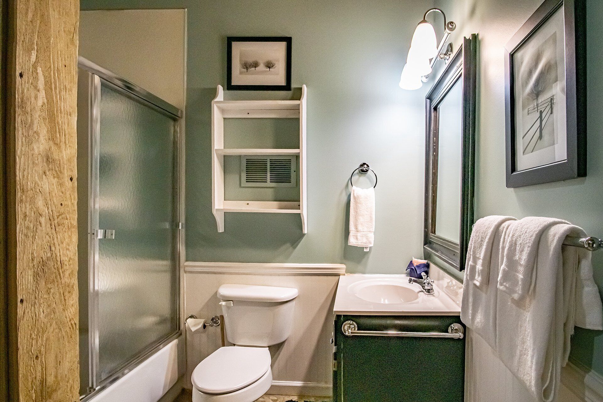 A bathroom with a toilet, sink, and a mirror. There is a towel rack with a towel hanging on it.