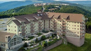 A multi-story hotel with a central courtyard, surrounded by lush greenery and hills in the background. - Soaring Eagle #201: 3 Bedrooms, 2 Full Baths: Slope Side (Snowshoe)