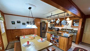 A kitchen with wooden cabinets, a central island, and hanging pots. - Lands End 4 BR Condo: 5 Mins Walk to the Village (Snowshoe)
