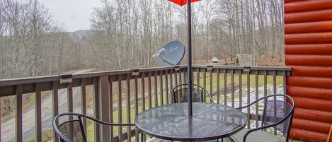 A covered outdoor seating area with a round table and chairs, a red umbrella, and a satellite dish.