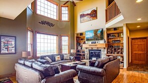 A spacious living room with leather sofas, a fireplace, and a large TV. - Top Property In Snowshoe 8 Br Nwr Rd 11 Luxury Home (Snowshoe)