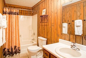 A bathroom with wooden paneling, a bathtub, a toilet, and a sink with a mirror. - Wabasso 10 Ski Hideaway Outside Your Door 2 Br Spacious Balcony (Snowshoe)