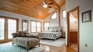 A spacious bedroom with a large bed, a sitting area with a sofa, and a wooden ceiling. - Top Property on Snowshoe Mountain North Westridge 32 is as Magnificent as its Western Views! (Snowshoe)