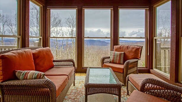 A sunroom with wicker furniture, large windows, and a view of mountains. - Top Property on Snowshoe Mountain North Westridge 32 is as Magnificent as its Western Views! (Snowshoe)
