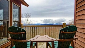 A wooden deck with two green Adirondack chairs and a small table, overlooking a mountainous landscape. - Top Property on Snowshoe Mountain North Westridge 32 is as Magnificent as its Western Views! (Snowshoe)