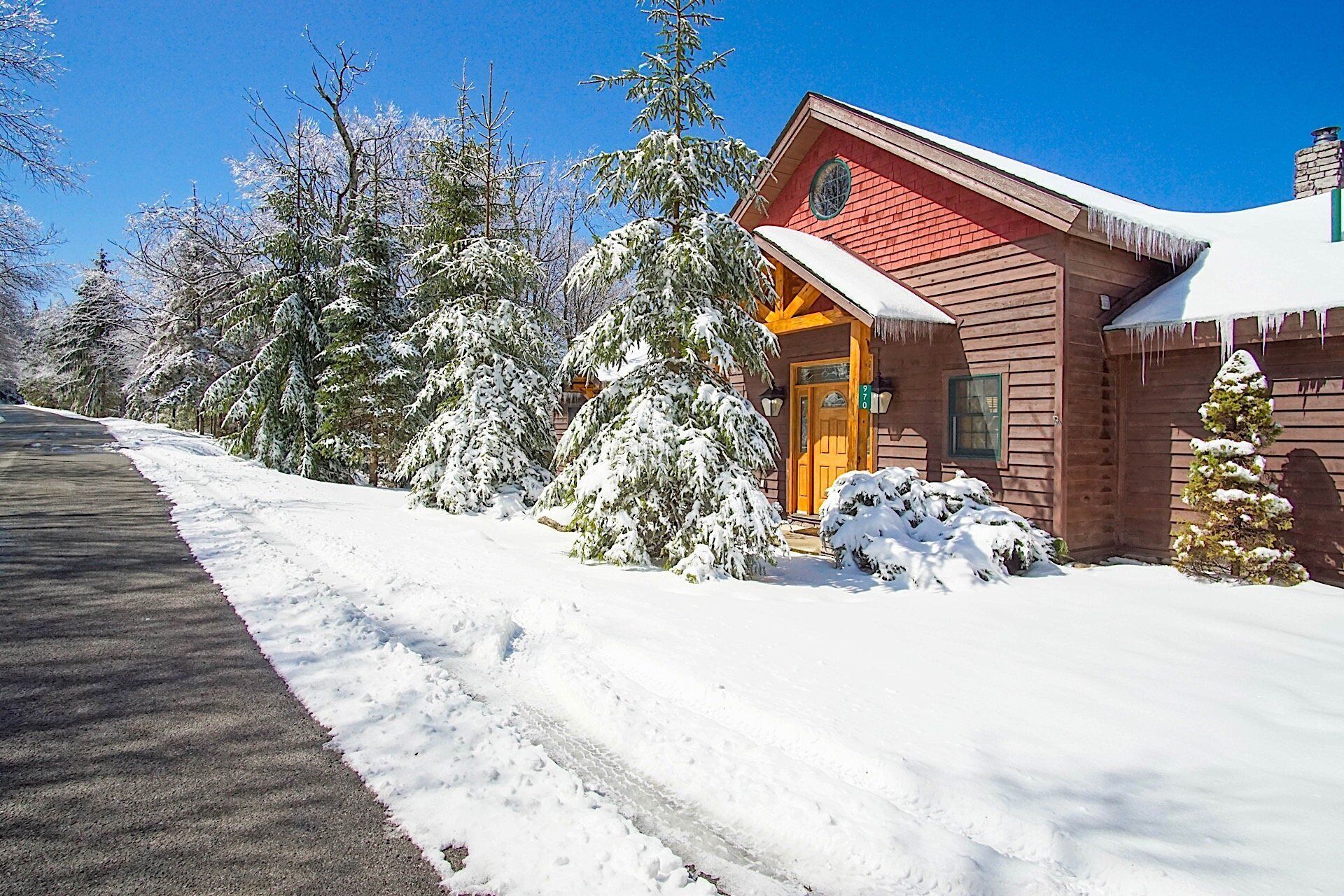 A wooden cabin with a red door, surrounded by snow-covered trees.