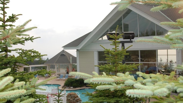 A modern building with a large glass facade, a swimming pool, and surrounding greenery. - Expedition Station #120: Snowshoe's Premier Slopeside Junior Studio Accommodations (Snowshoe)