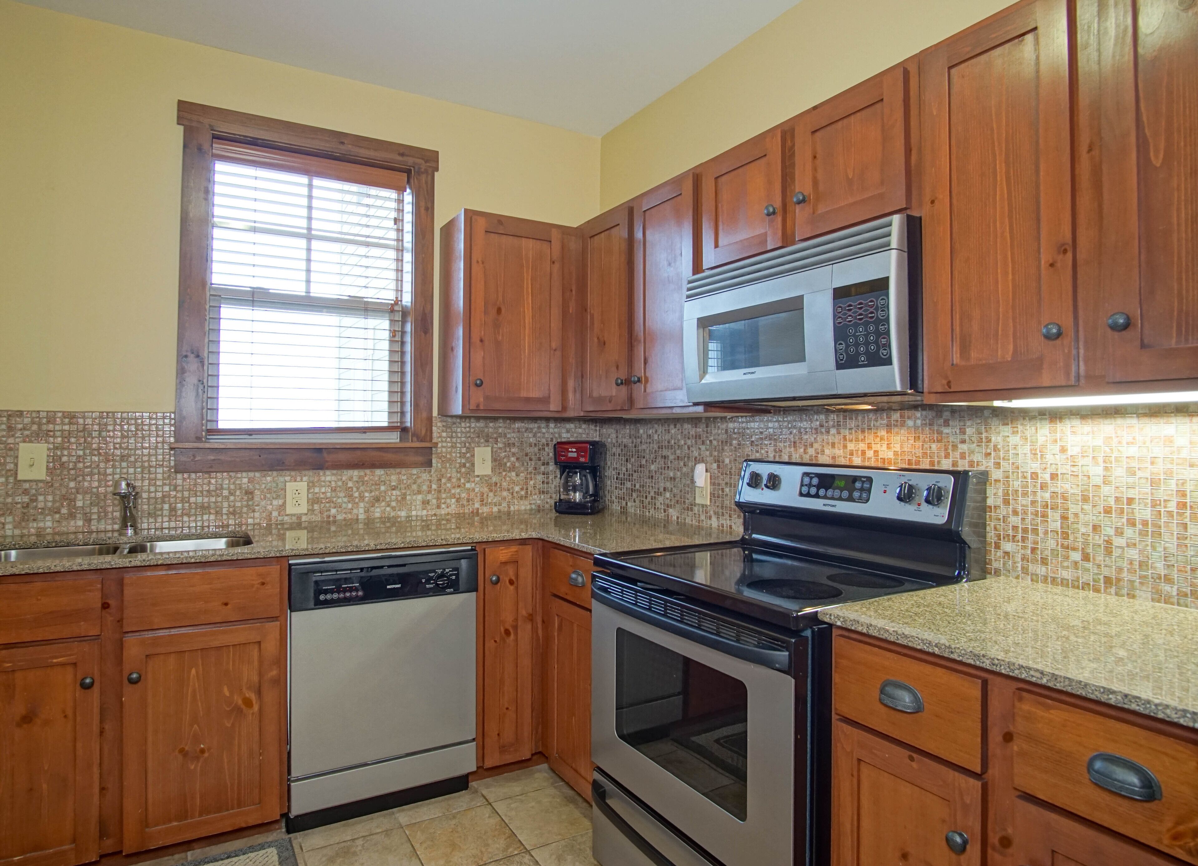 A kitchen with wooden cabinets, a microwave, a stove, and a dishwasher.