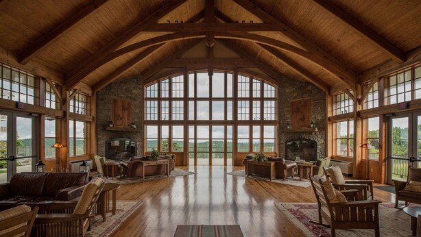 A spacious room with high ceilings and large windows, featuring a fireplace, wooden furniture, and a view of the outdoors. - 2 Br: Soaring Eagle Lodge 317: Luxury Bell Tower Condo - Great Amenities -slope Side (Snowshoe)