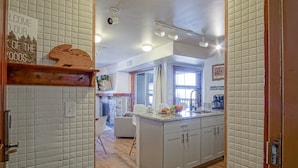 A kitchen with white cabinets, a wooden countertop, and a stone fireplace. - Rimfire 342: Memory Maker, Walk to Shops, Slope Side (Snowshoe)