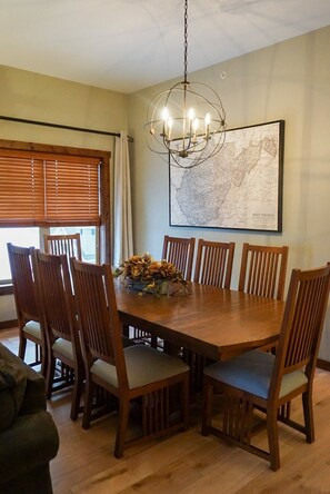 A dining room with a wooden table, six chairs, a chandelier, and a map on the wall. - Soaring Eagle #405: 3 Br Location! Slope Side, Hot Tub (Snowshoe)