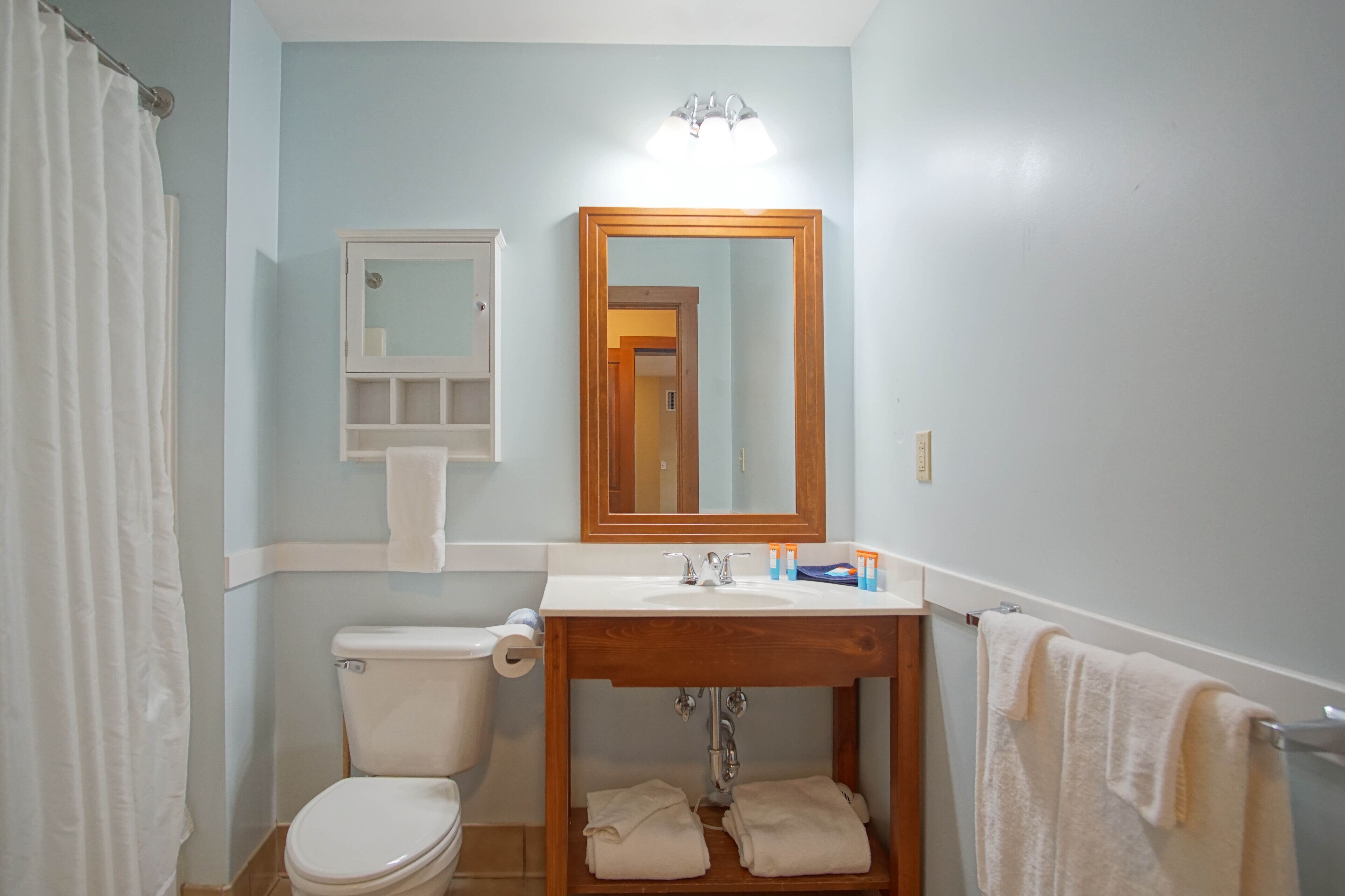 A bathroom with a toilet, sink, mirror, and towel rack.