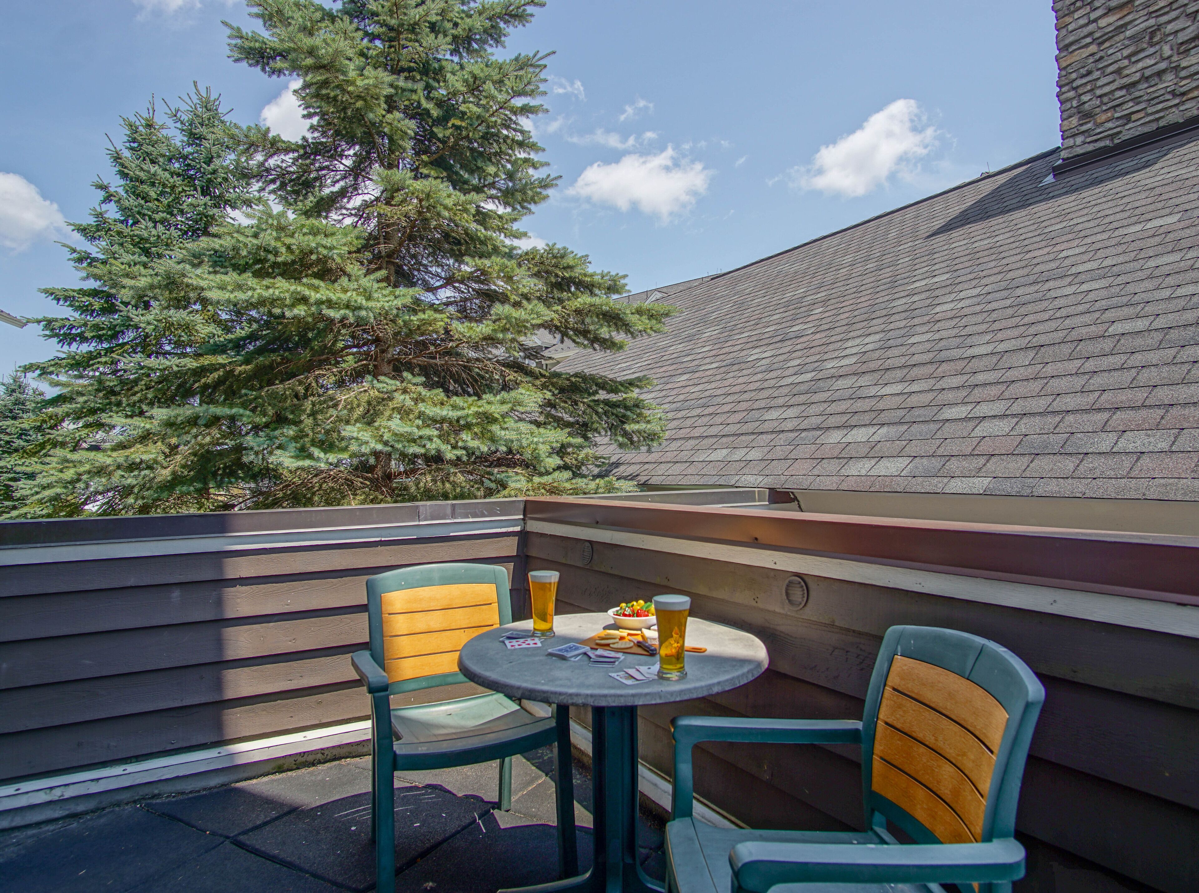 An outdoor seating area with two chairs and a table, a beer mug, and a bowl of snacks.