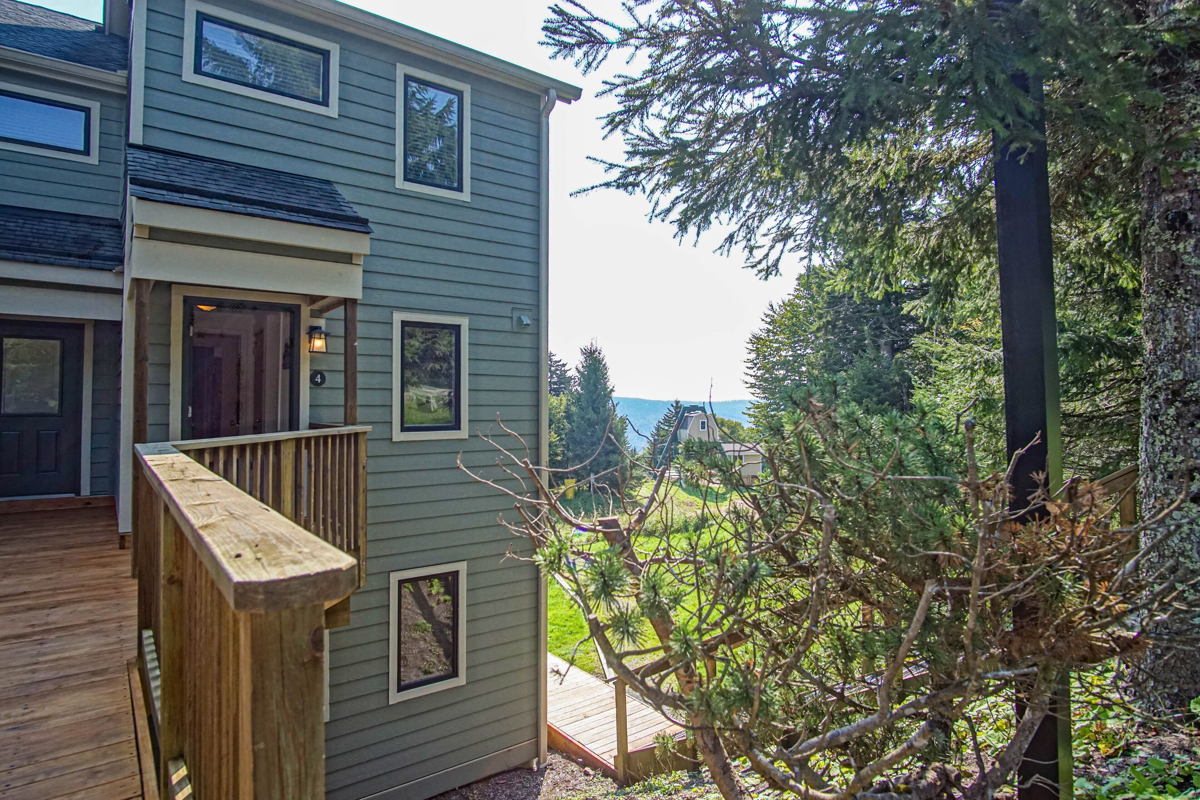 A two-story building with a wooden deck and a view of a forested area.