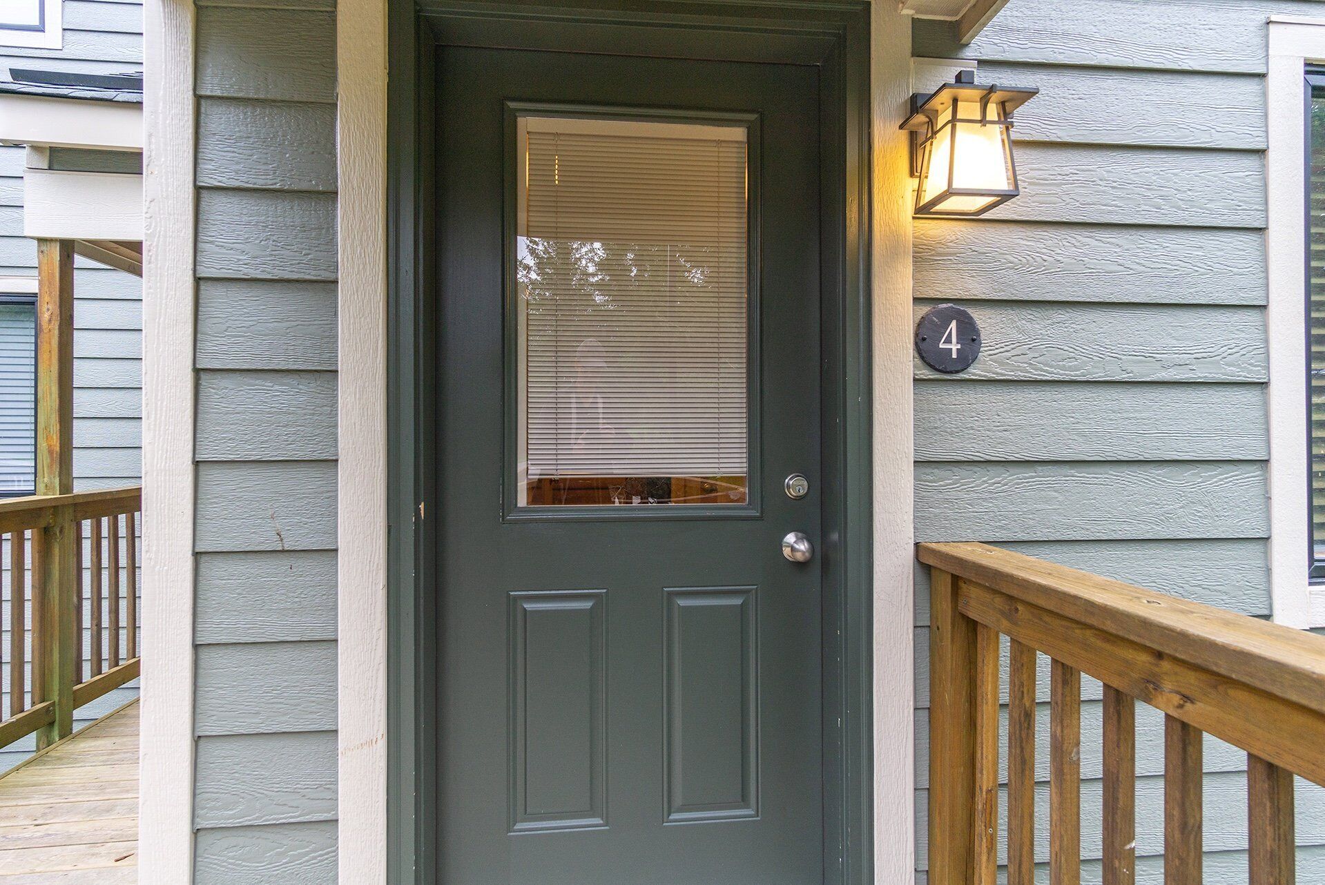 A dark grey door with a window, a wooden deck, and a house number '4'.