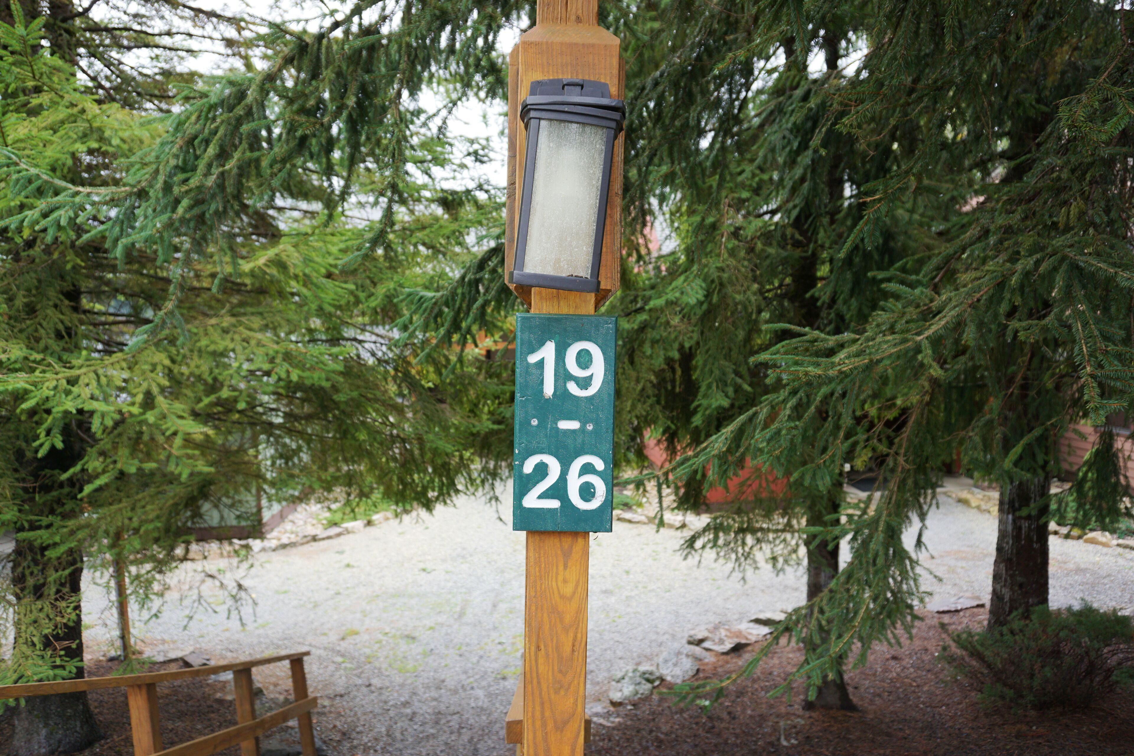 A wooden post with a green sign displaying the numbers 19 and 26.
