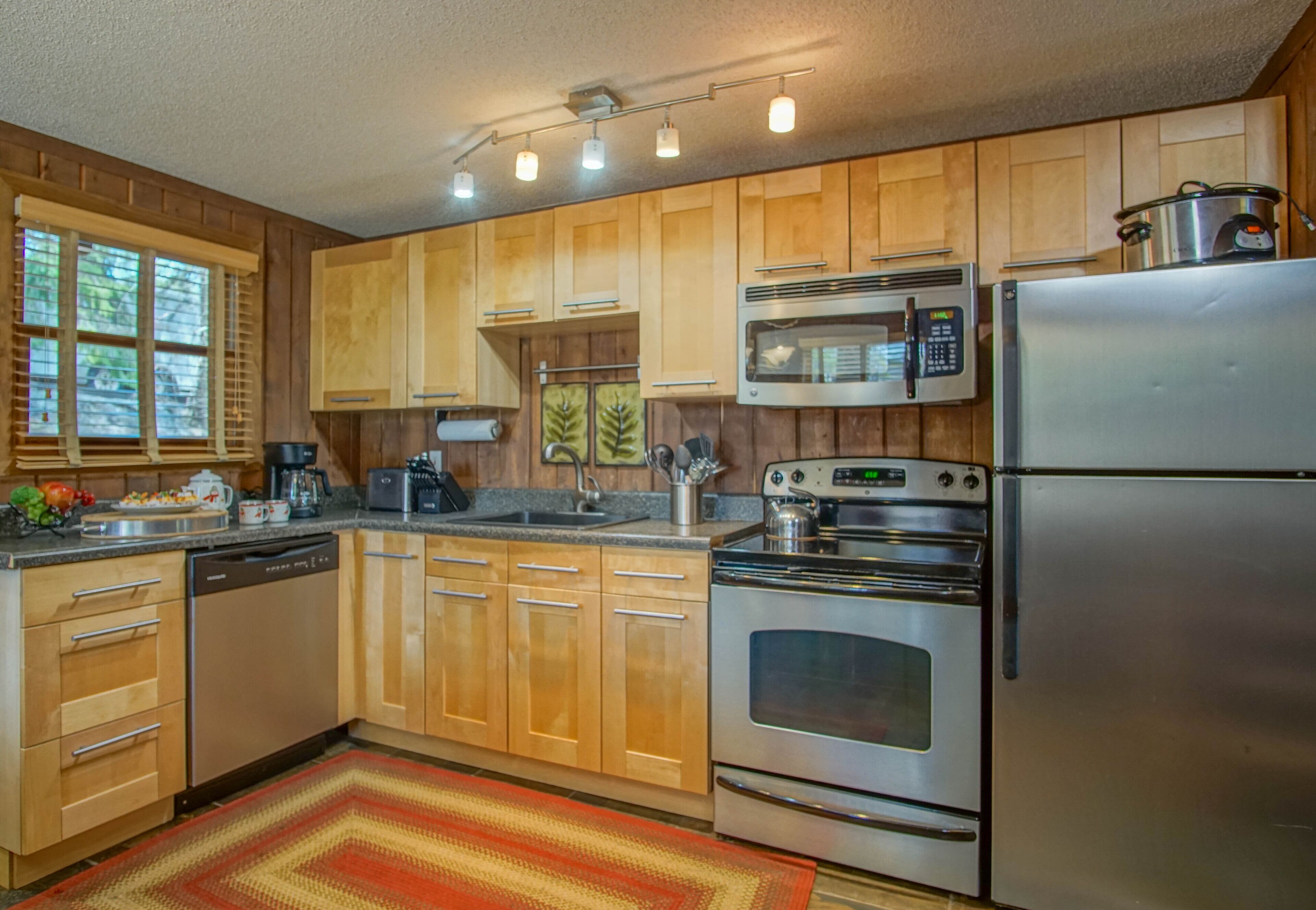 A kitchen with wooden cabinets, stainless steel appliances, a microwave, and a refrigerator.