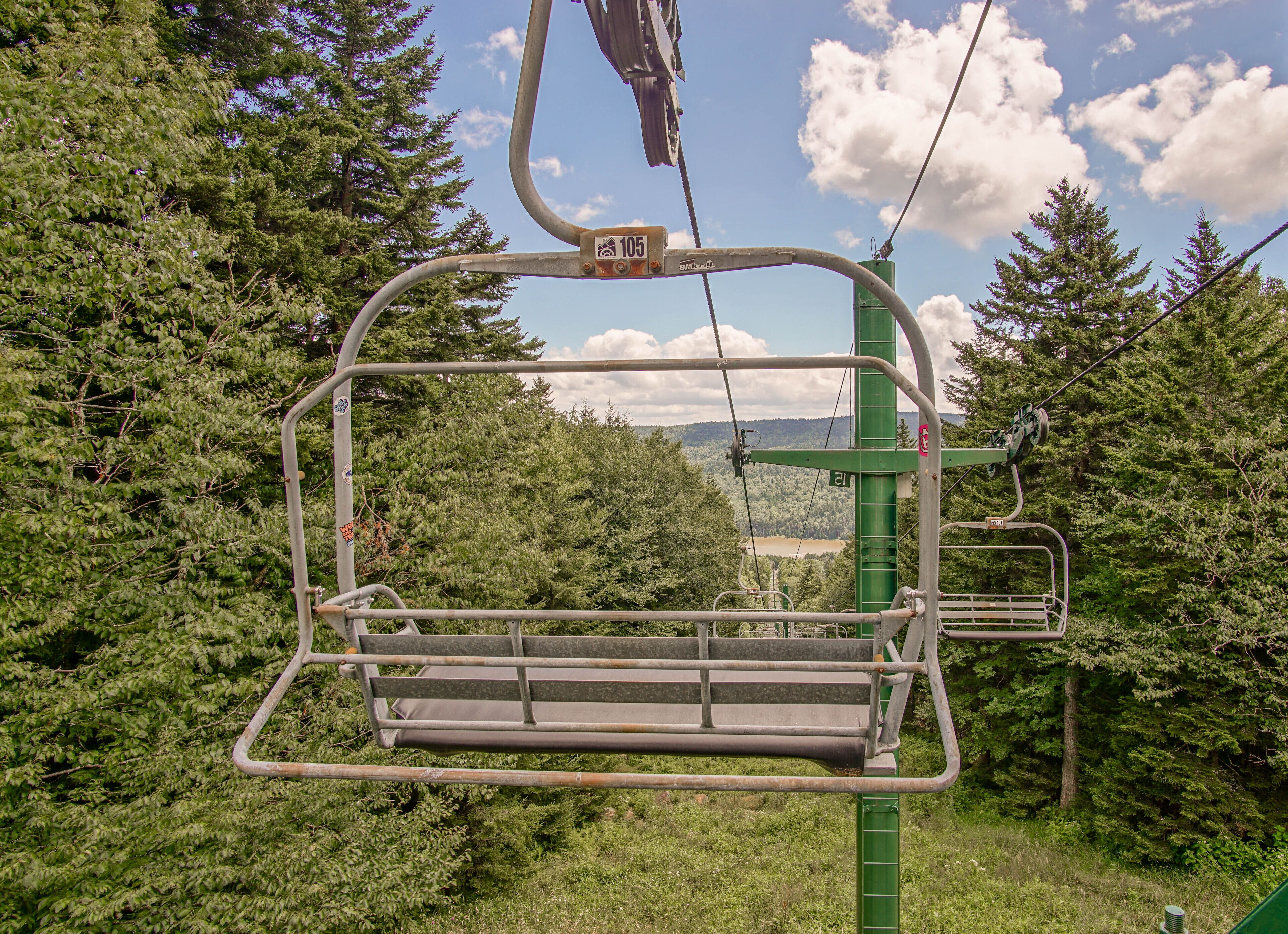 A chairlift in a forested area with a clear view of the landscape.