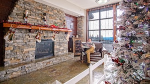 Una sala de estar acogedora con chimenea de piedra, un árbol de Navidad y un sillón de cuero.