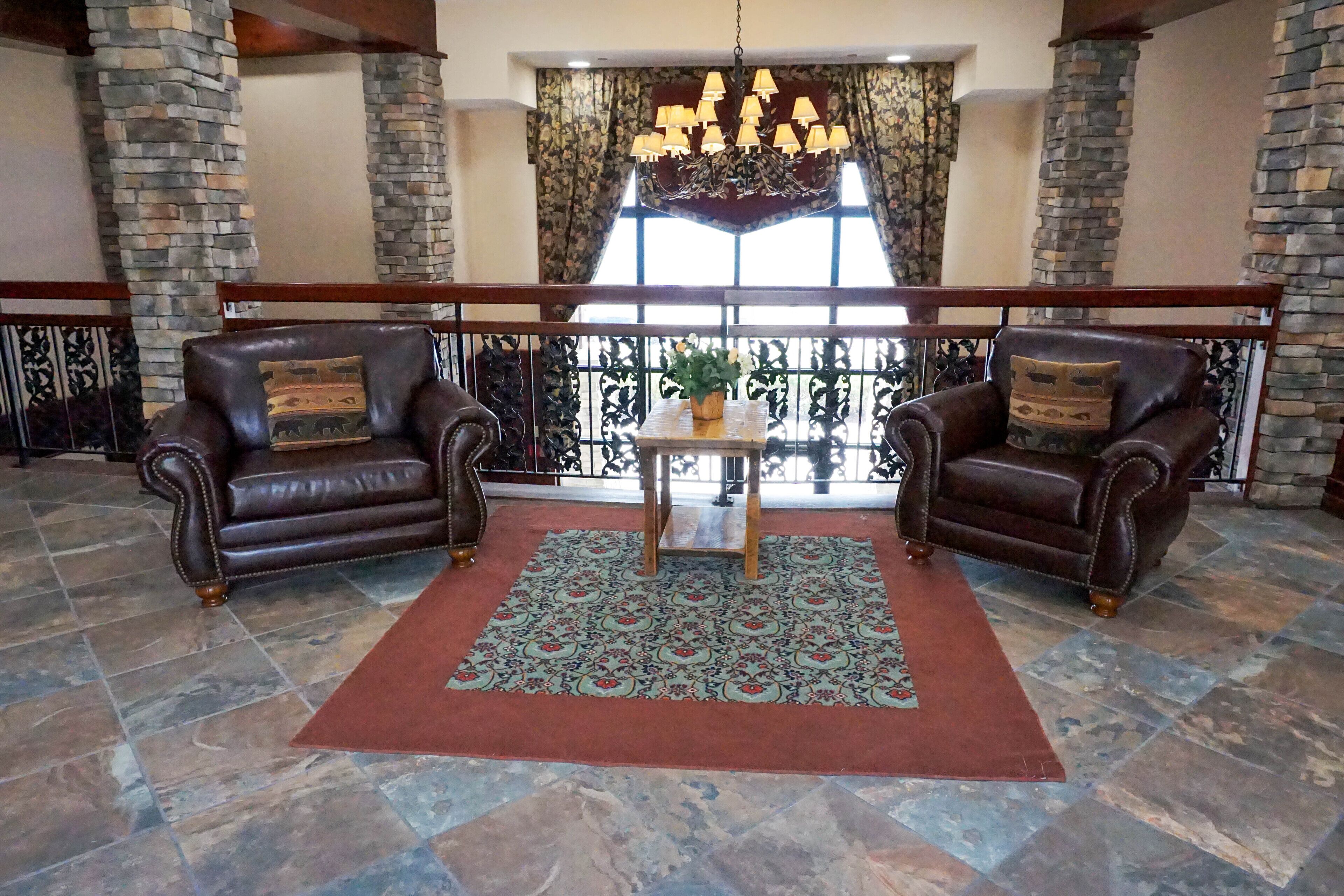 A spacious lobby with two leather armchairs, a wooden coffee table, and a patterned rug.